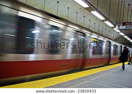 red line train on the boston mbta in motion pulling into the subway station stop with person waiting