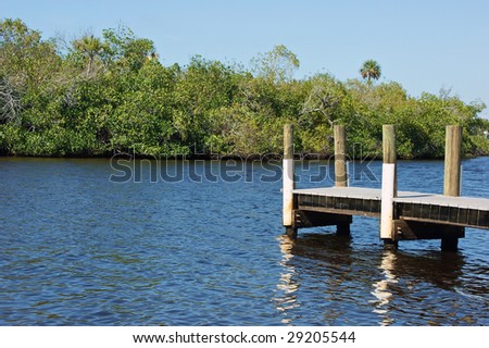 pier over water with trees in background with reflections in the rippling water