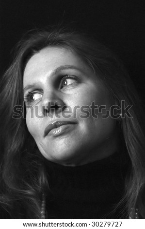 portrait of attractive woman with head tilted back looking looking off to the side with a slight smile on her face in black and white. side lighting
