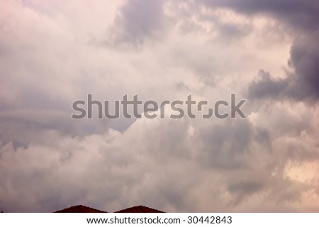 beautiful cloudscape of storm clouds gathering over roof tops with lots od space for copy could be used as a background