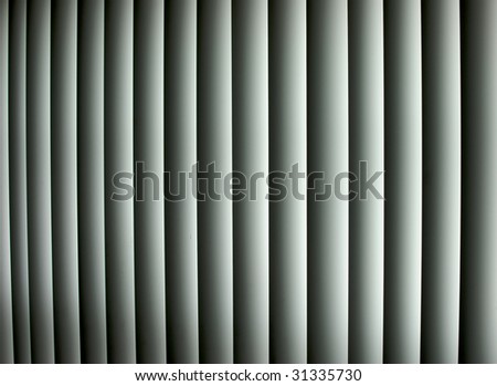 Closed vertical window blinds with sun light shining through make up this abstract image, Suitable as a background or wallpaper.