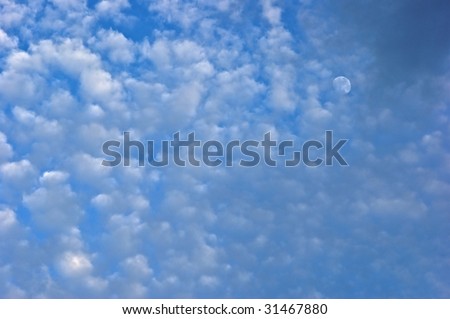 small white puffy clouds lead the viewers eyes to the moon in the upper right of this cloudscape. also suitable as desktop background or wallpaper.