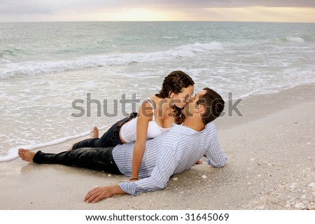 stock photo young adult couple kissing at the beach as the sun sets