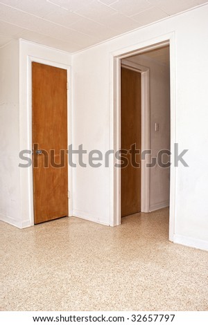 two closed doors and an open doorway on white walls.