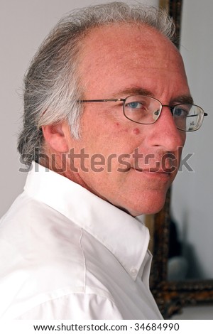 portrait of handsome man turned looking at viewer with a slight smile in white dress shirt.