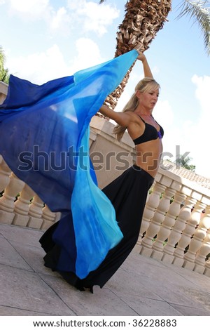 pretty blonde belly dancer in black arching back while dancing outside on balcony