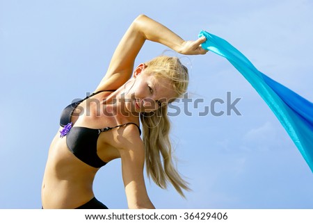 outdoor portrait of attractive blonde belly dancer arching back making eye contact with the viewer against  powder blue sky