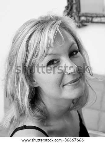 looking down towards a beautiful blonde woman that is looking at viewer with shoulders turned and a small smile on her lips, black and white image