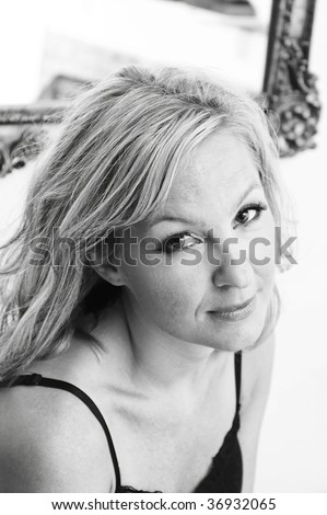 beautiful blonde woman with big eyes is looking up at viewer with slight smile on face, black and white image