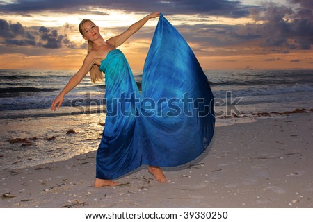 A beautiful blonde female dancer on the beach at sunset with waves crashing in the background.