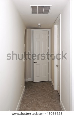 a white door is ajar at the end of a hallway