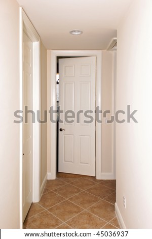 a tiled hallway with a white door slightly open at the end
