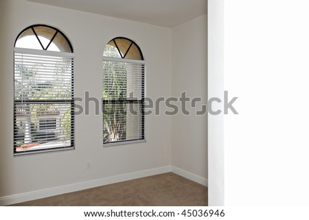 looking into empty room that has two arched windows with copy space on nearest wall.