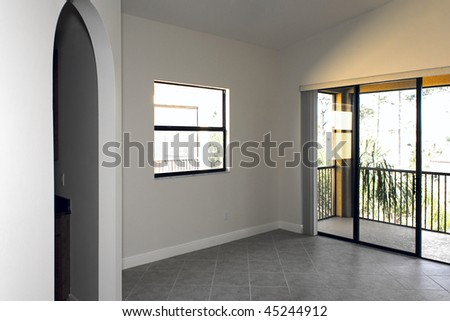 large empty room with arched doorway, window, and sliding glass doors