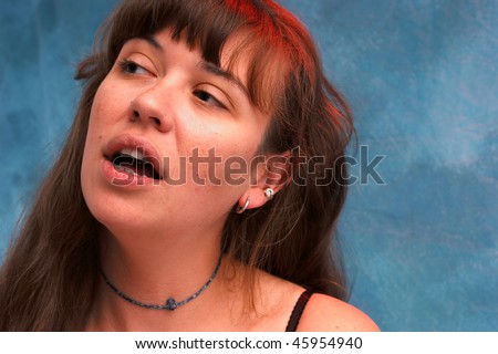 Portrait of a beautiful young woman looking to the left with her mouth open as if speaking, shot with red and blue strobes to enhance colors.
