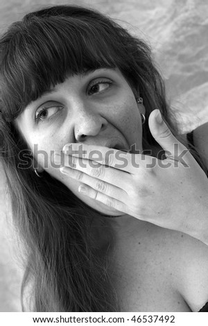 black and white image of beautiful brown haired woman covering her mouth as she yawns and looks tired.