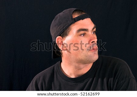 studio profile portrait of a man in black street clothes wearing a black cap and black t shirt