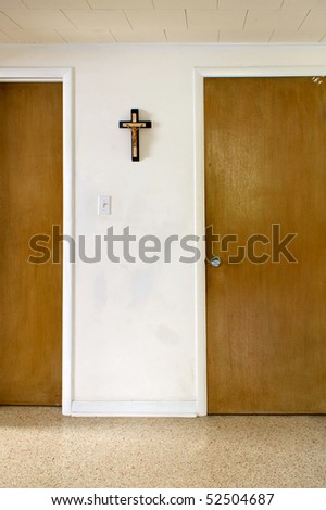an old room with patched painted walls, a crucifix and two closed doors in an old florida home