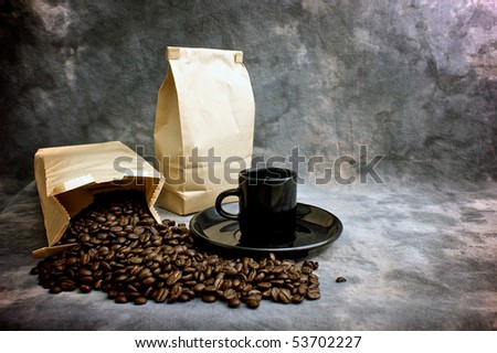 Fine art image of coffee showing a bag of whole beans, a closed bag of coffee and a black espresso cup on a saucer against a mottled studio background.  Logo or text can be placed on blank bag.