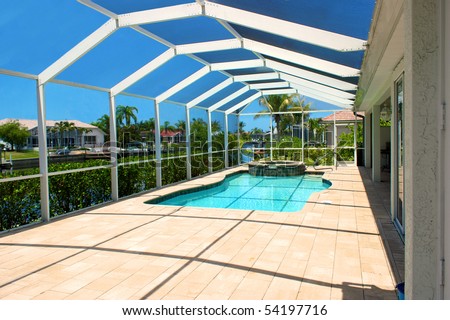 wide angle view of screened in pool and lanai in florida with blue sky and canal