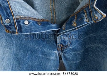 An open pair of old worn out button up blue jeans. showing open fly.