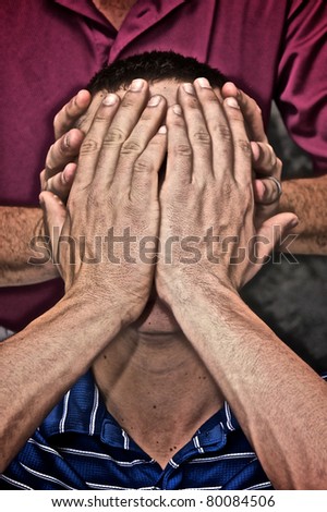 A man is hiding his face by holding his hands in front of it while another man holds the sides of his head in this highly detailed image..