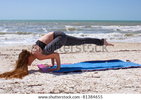 an athletic brown haired woman is doing yoga exercise Galavasana or sage pose on an empty beach at the gulf of mexico in bonita springs florida