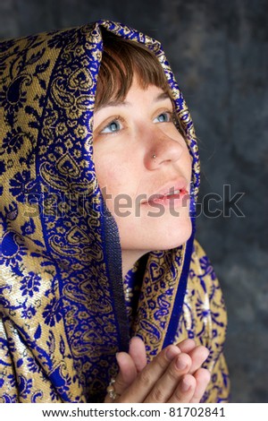 Portrait of a beautiful brown haired woman in profile, looking up as if in prayer, her head is wrapped in an exotic shawl and she looks pleased or happy.