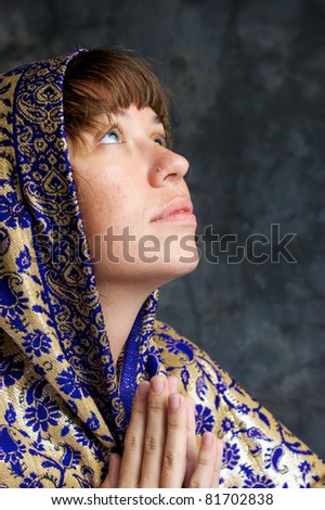 Portrait of a beautiful brown haired woman in profile, looking up as if in prayer, her head is wrapped in an exotic shawl.