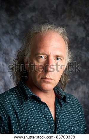 A blue eyed mature white american male wearing casual dress shirt looking at viewer.