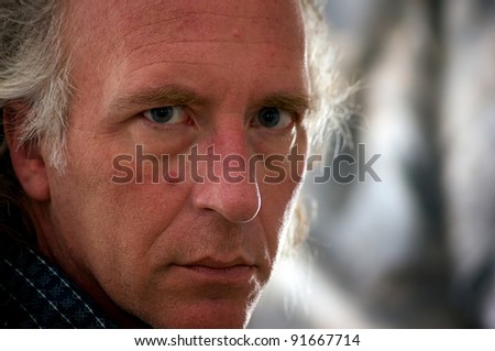Close up portrait of older blue eyed white male looking directly at viewer.