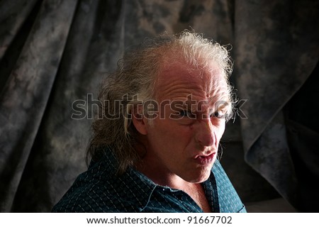 White man making funny face in studio with wrinkled brow.