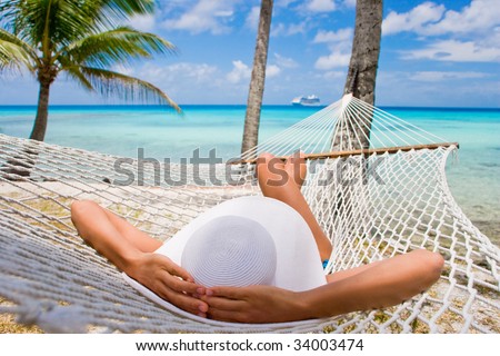 Woman relaxing on hammock with white hat sunbathing on vacation