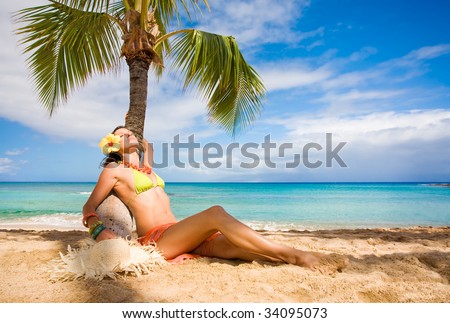 attractive woman sunbathing on tropical beach under palm tree