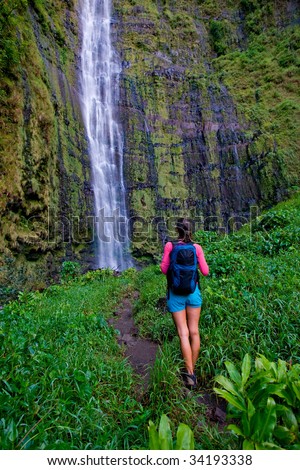 active healthy woman on hike to waterfall with backpack in hana maui, hawaii