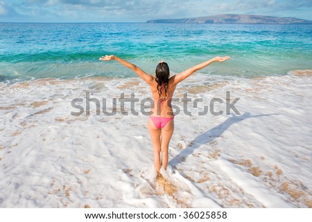 woman in pink bikini on tropical beach with arms outstretched happy and free in maui, hawaii