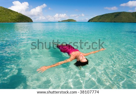 woman floating with sarong in turquoise waters at colorful tropical beach