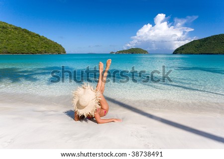 woman laying on tropical beach stretching with shapely body curves in caribbean