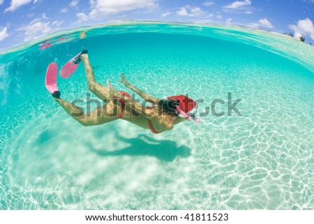 woman with red bikini snorkeling with holiday christmas hat underwater in tropical island paradise