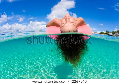 woman floating on tropical pink inflatable inner tube in tropical water in virgin islands, caribbean