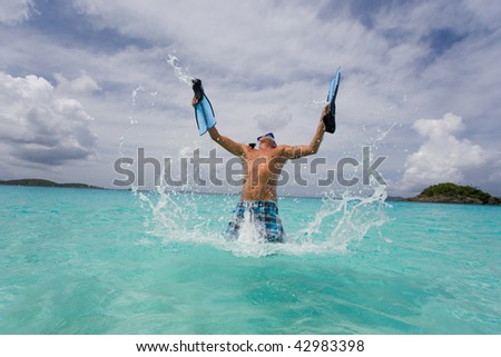 man with snorkel gear jumping in tropical island water