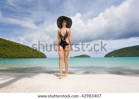woman on beach in elegant black bikini and hat on caribbean vacation