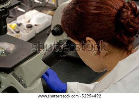 lab tech looking through microscope at a tissue sample