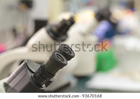 microscope eyepieces in a lab, with out of focus lab equipment backdrop