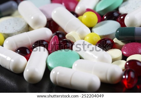 Colored glossy rounded multi vitamin pills macro shot over black background
