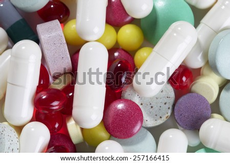 Colored glossy rounded multi vitamin pills macro shot over white background