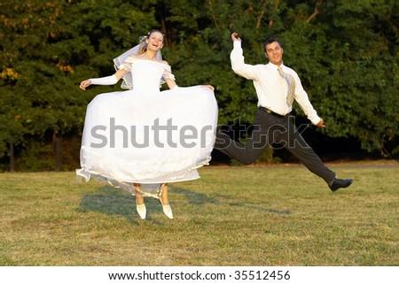Happy wedding couple jumping in the summer park