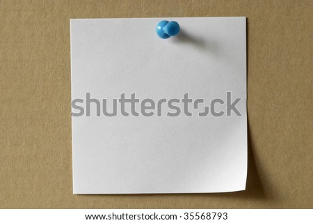white sticker note with a blue push-pin over cardboard