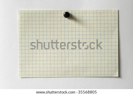 White checked note with a black push-pin over white paper