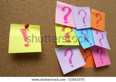 Sticker notes with exclamation and question signs over cork notice board